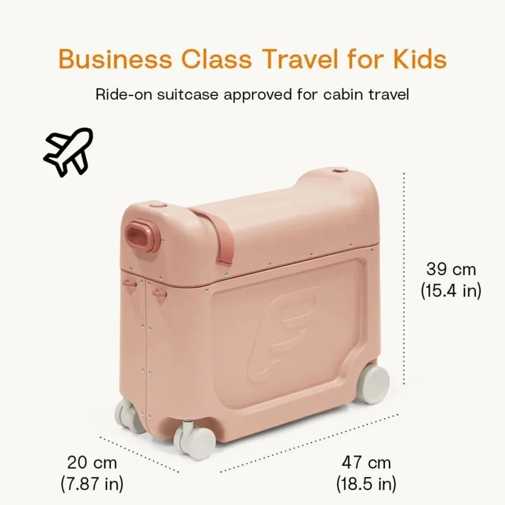 Coral pink kids BedBox ride-on suitcase with handle and large wheels in travel setting