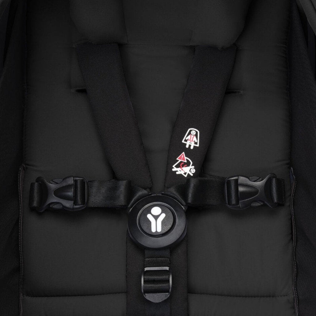 Black newborn harness with padded straps and central buckle clip