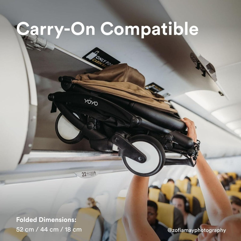 Folded black stroller with handle held for travel, on compact frame