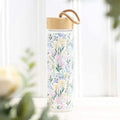 Floral glass water bottle with bamboo lid and carrying loop, pastel wildflower print