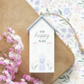 Hanging house decoration with 'Our happy place' text, blue roof, floral accents