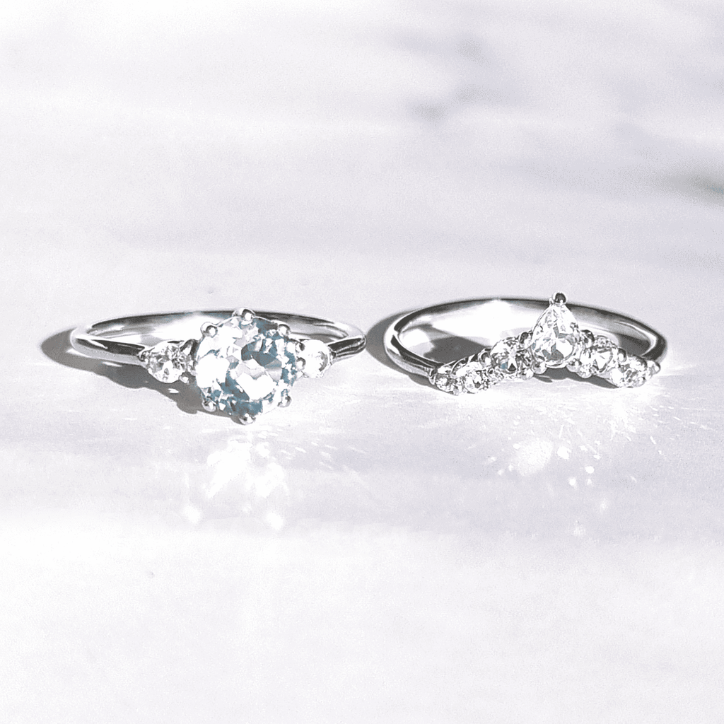 Two sterling silver rings with oval blue gemstone centers and clear stone accents