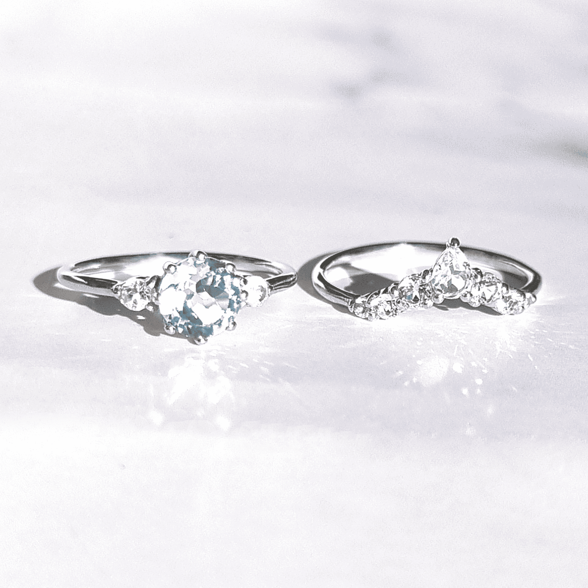 Two sterling silver rings with oval blue gemstone centers and clear stone accents