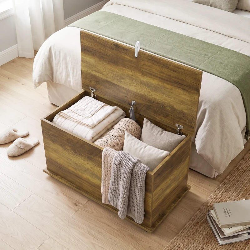 Brown storage chest with hinged lid open, showing folded linens inside.