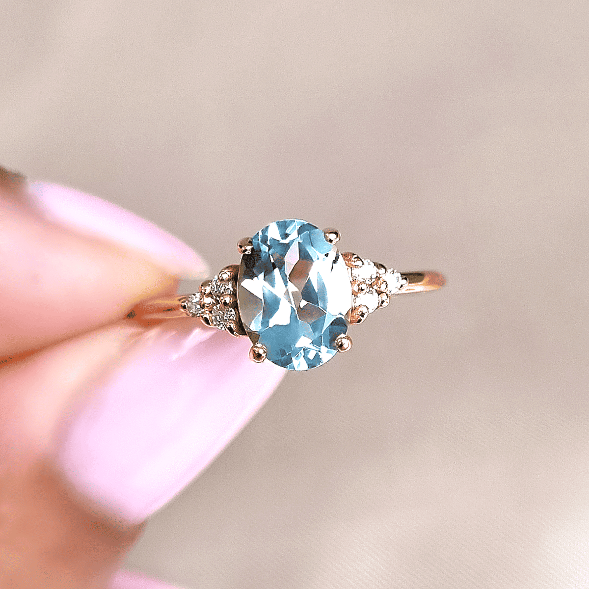 Oval sky blue topaz ring with small round side stones, shown close-up