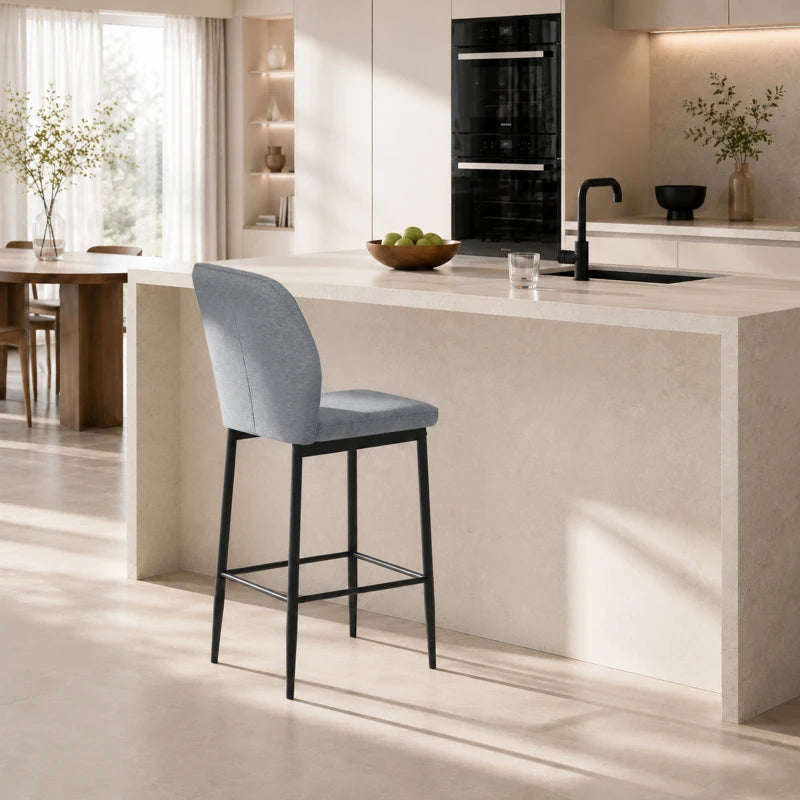 Grey velvet bar stool with curved backrest and footrest, black metal frame