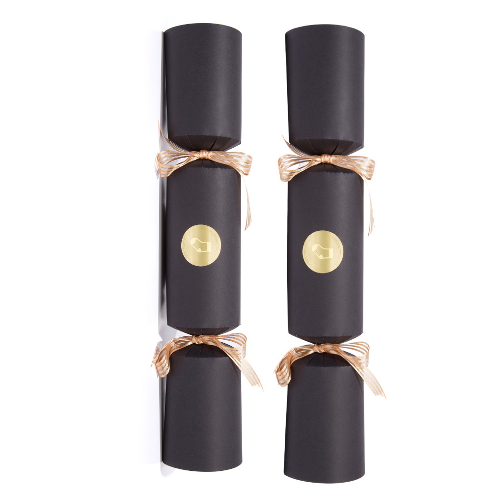 Two black Christmas crackers with gold ribbons and a gold button on a white background