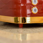 Close-up of red kettle base with gold trim and control dials