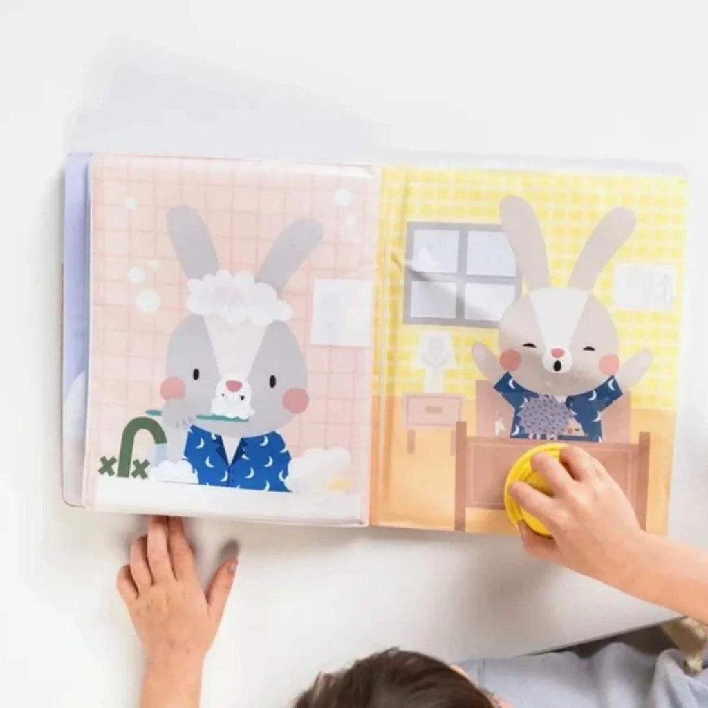 Open peek-a-boo water book with bunny and rabbit characters; yellow stamp in hand