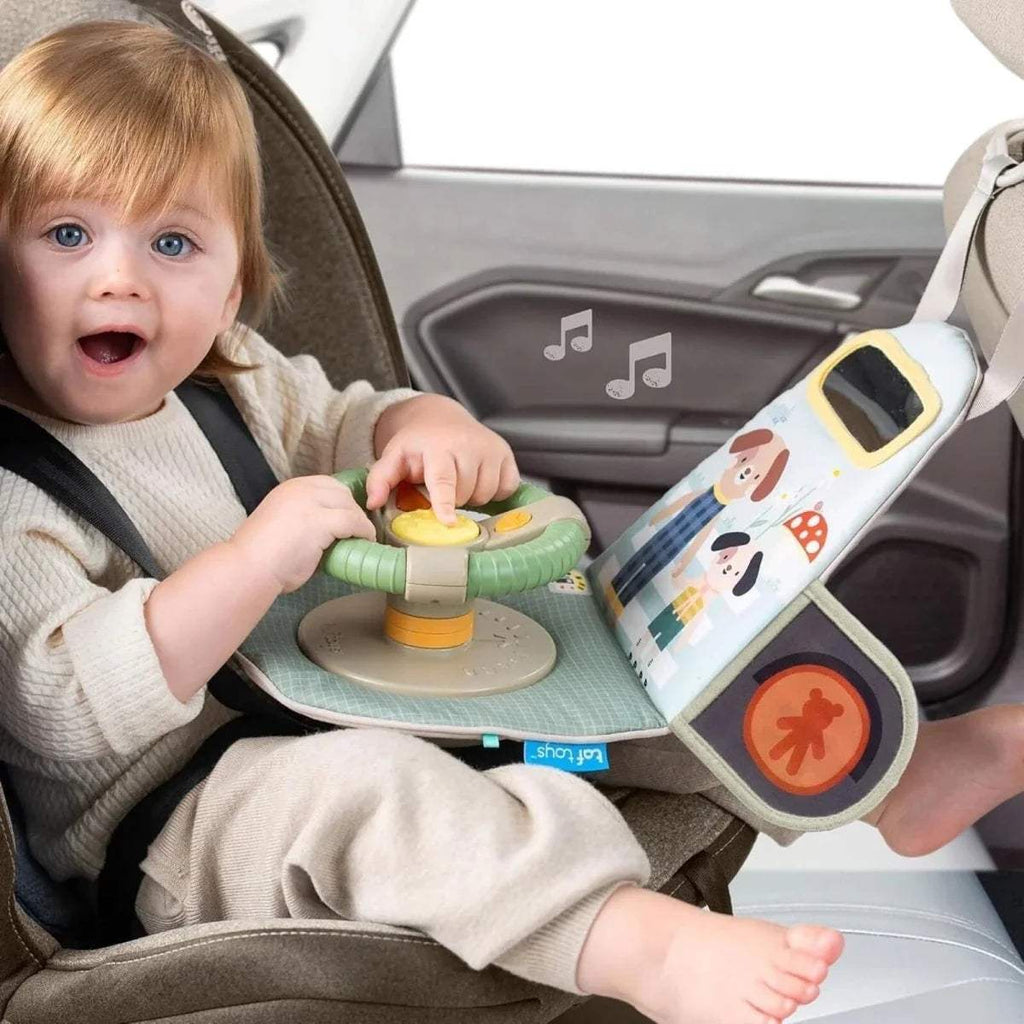 Baby playing with car travel toy dashboard: green steering wheel and traffic light section