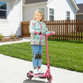 Pink electric kids scooter with rider standing on the deck and front wheel