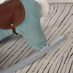 Blue plush rocking horse on gray rocker base, resting on patterned rug