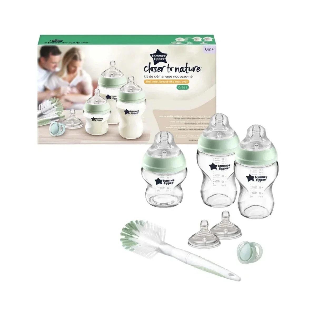 Baby bottle starter kit with two mint-topped glass bottles, brush, and caps