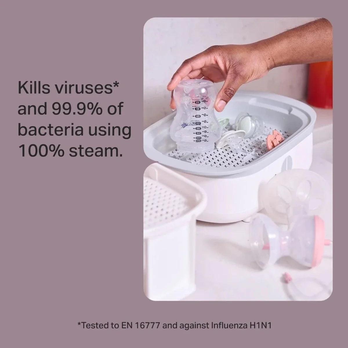 Electric steam steriliser with open white chamber and basket holding bottle parts