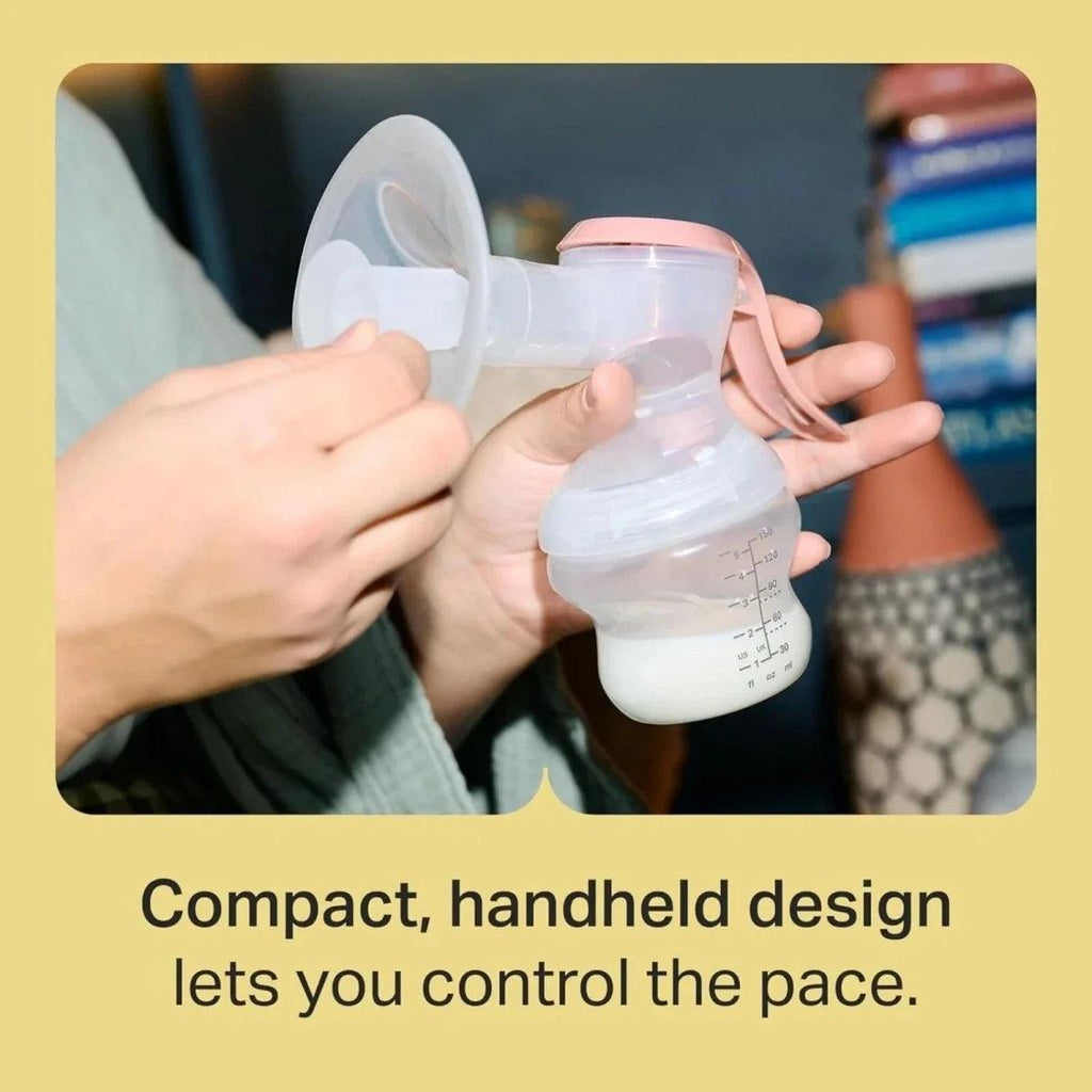 Handheld manual breast pump with clear bottle and pink handle held in hands