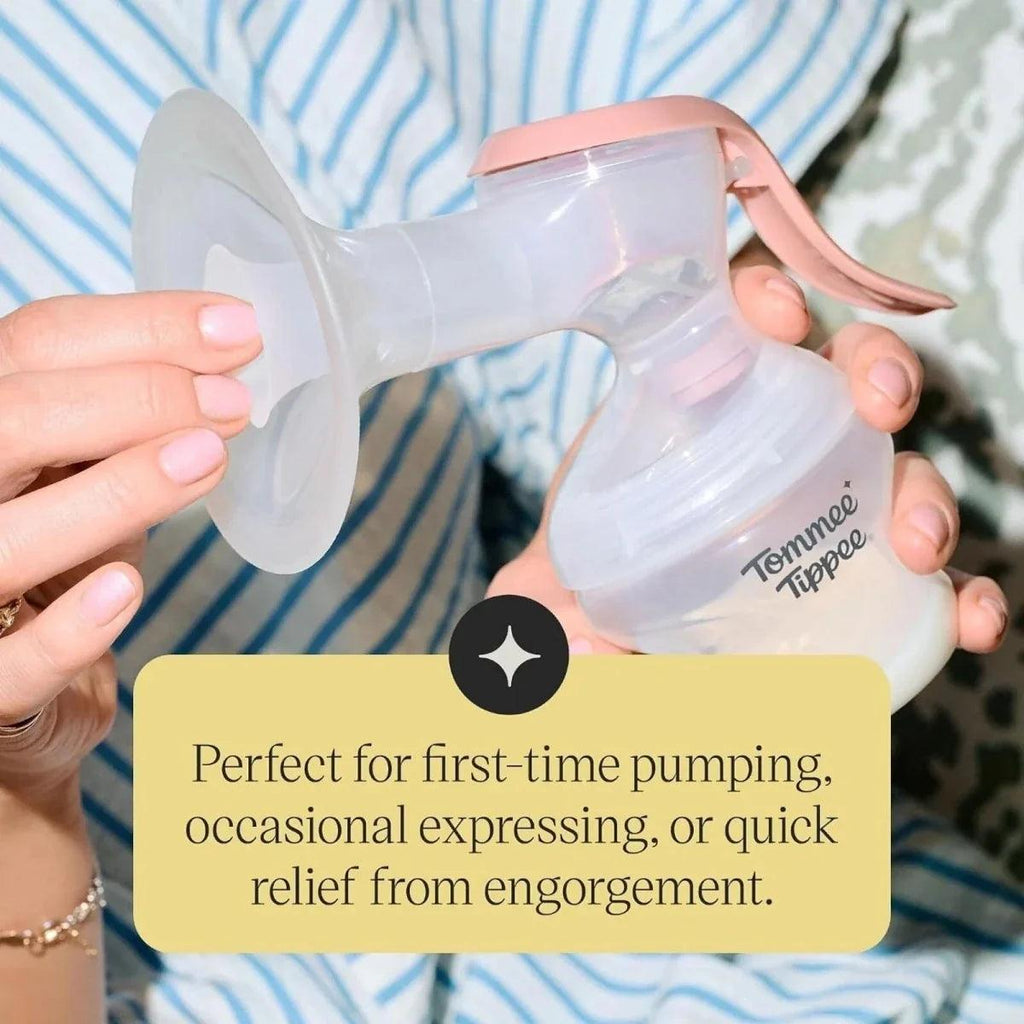 Manual breast pump with clear bottle and pink handle held with hands