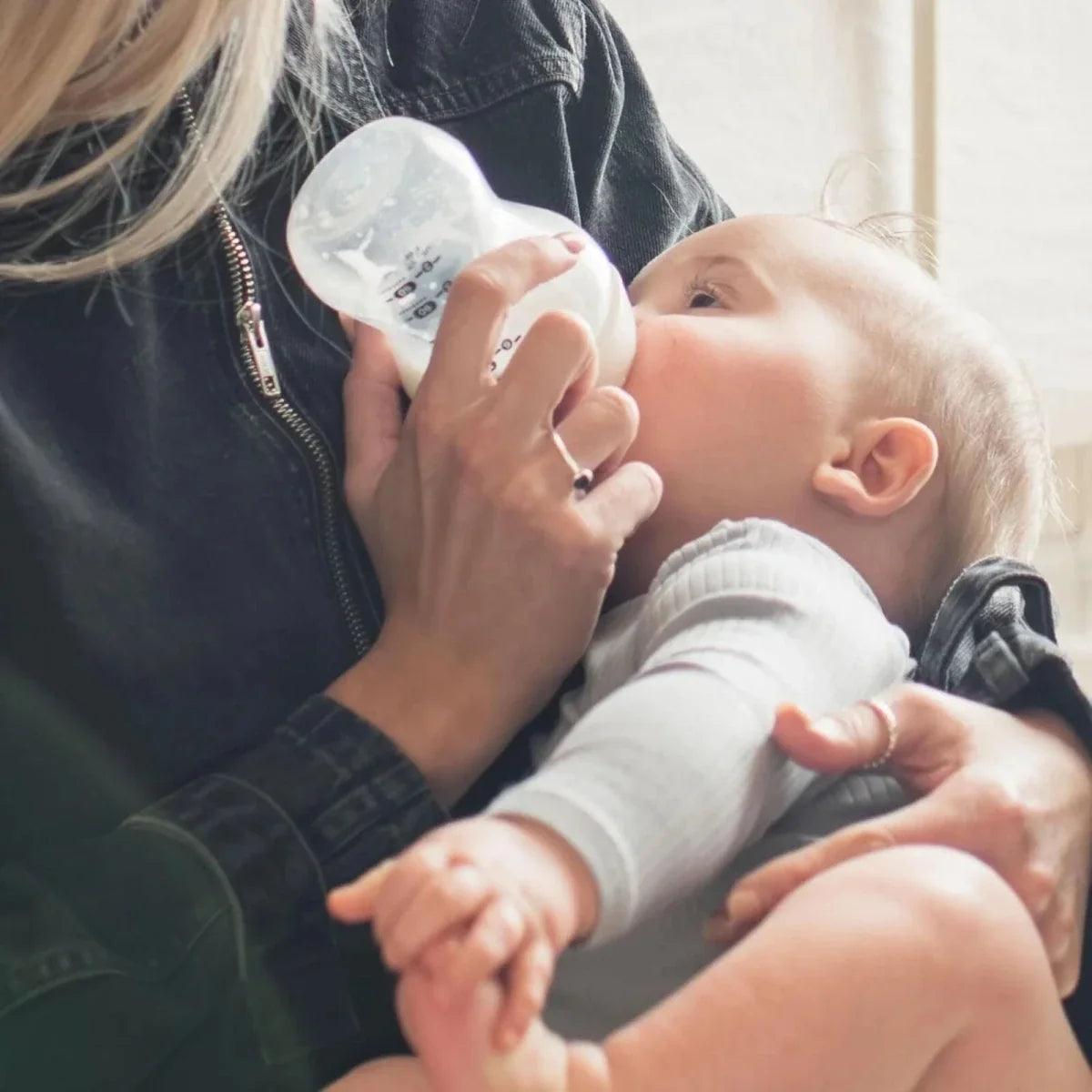 Feeding bottle with transparent nipple, held for infant feeding