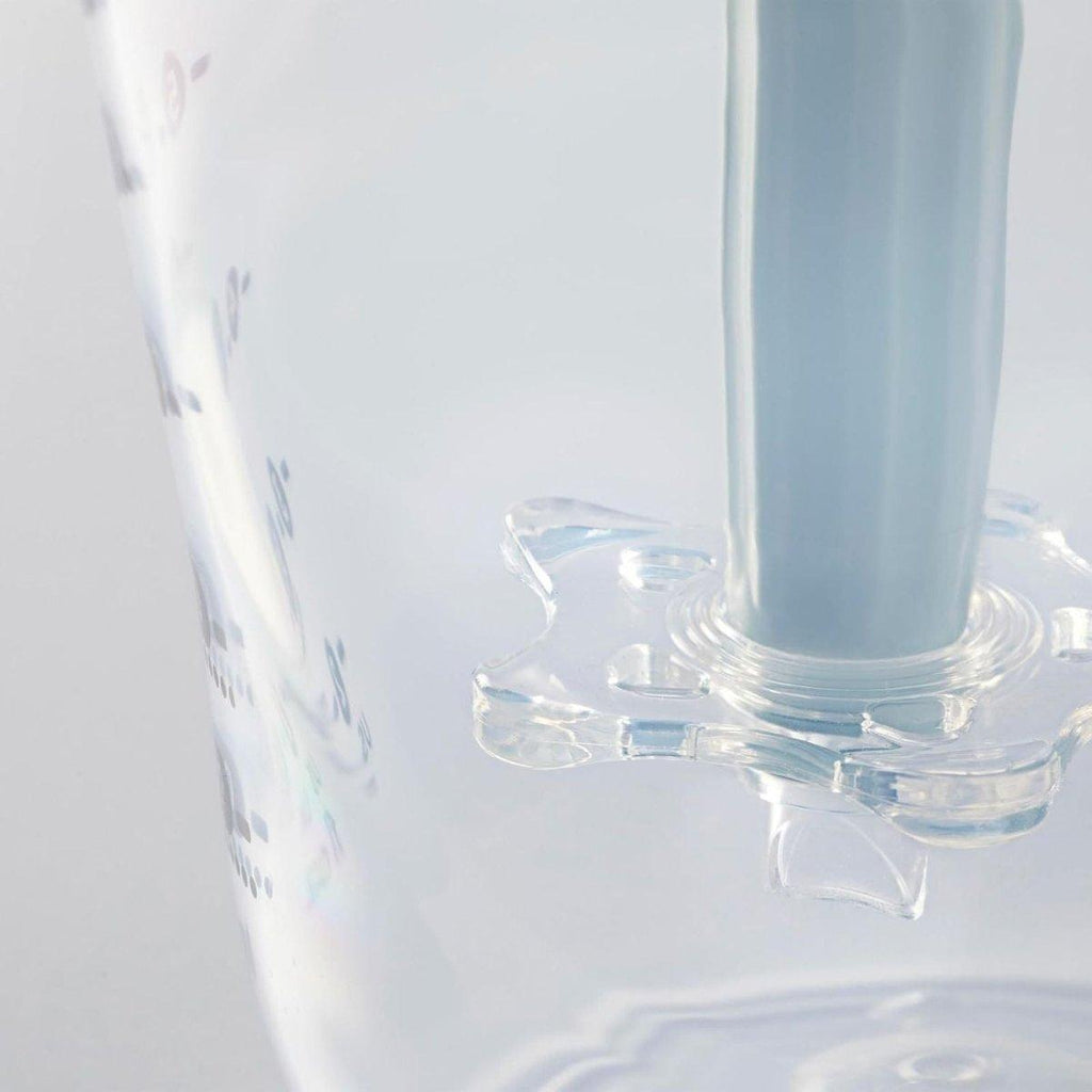 Transparent baby bottle close-up next to bottle-warming stand