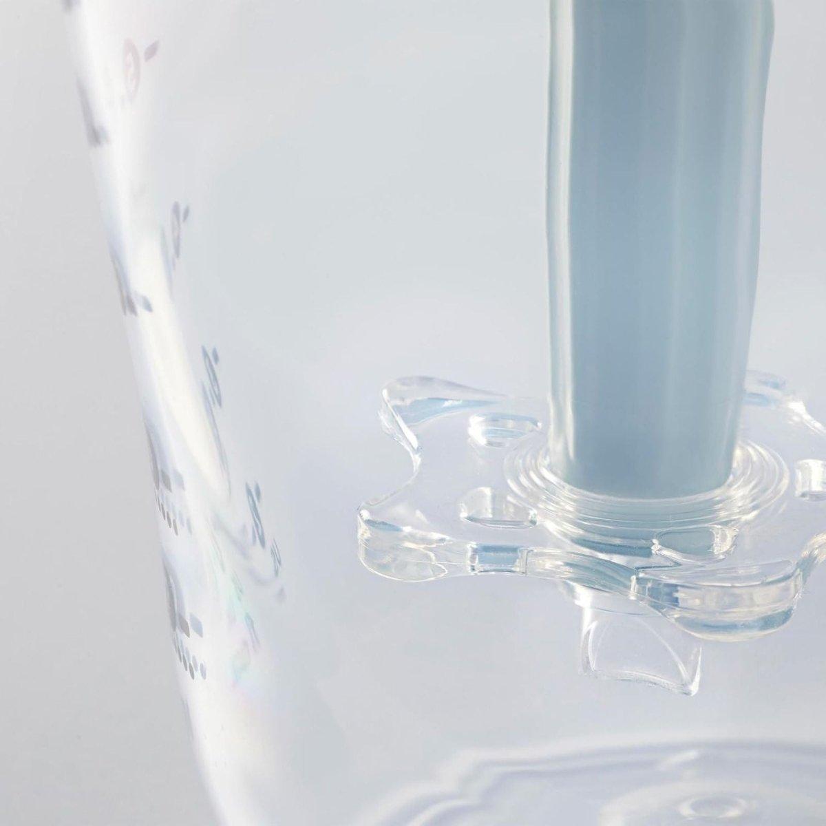 Transparent baby bottle close-up next to bottle-warming stand