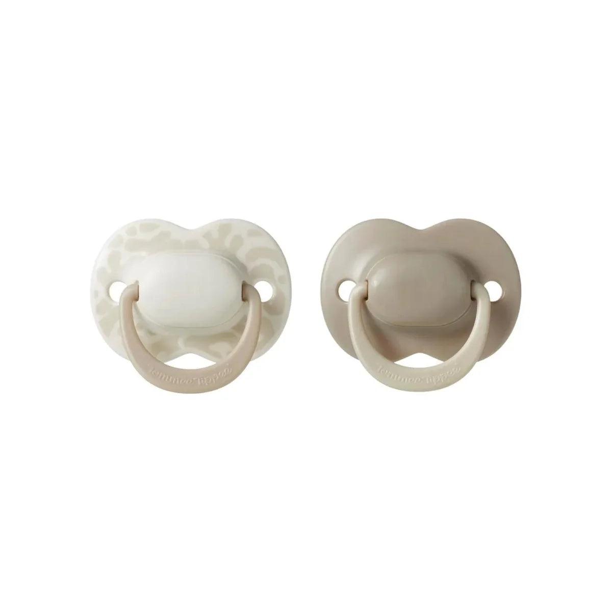 Two latex soothers: one solid cream, one patterned cream with green shield.