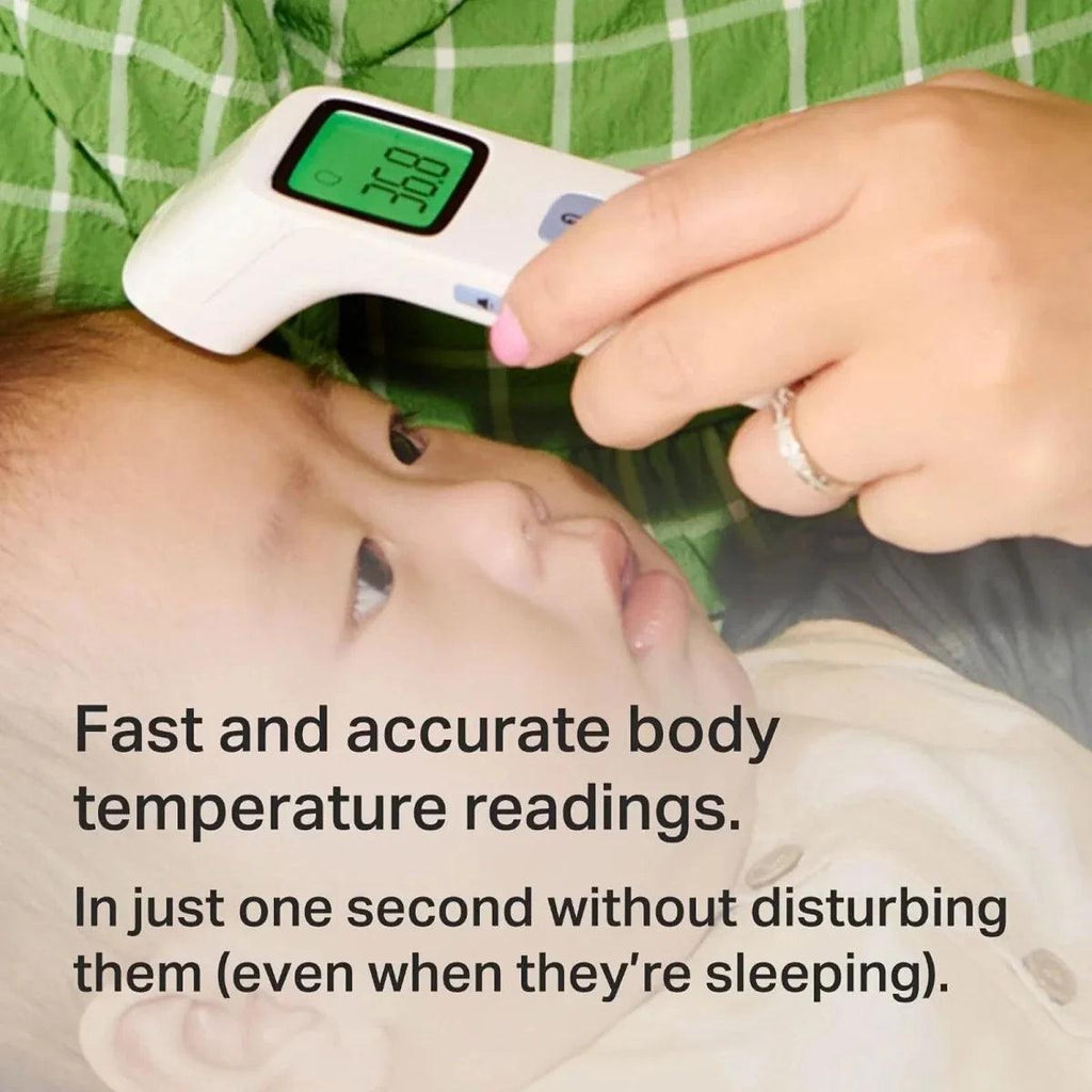 No-touch digital forehead thermometer near sleeping baby's face, green LCD reading