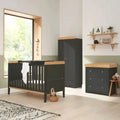 Dark slate cot bed with slatted sides and light wood mattress base, plus changing table