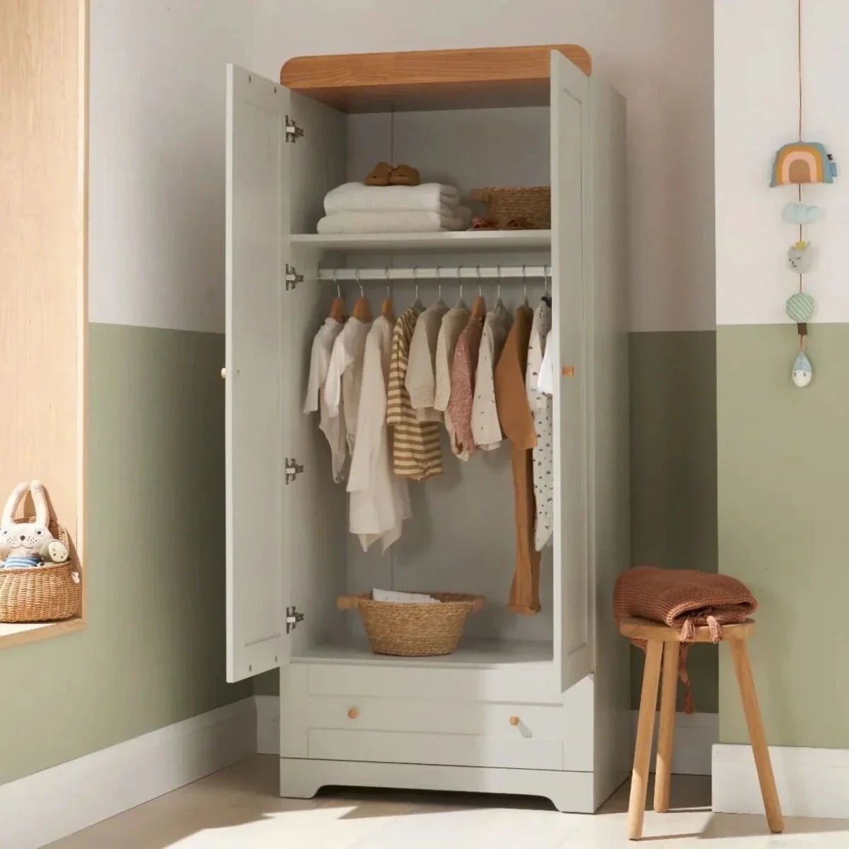 White wardrobe cabinet with open doors, hanging clothes, honey oak top trim