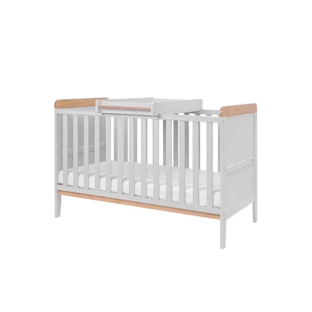 White cot bed with slatted sides and honey oak rails, elevated mattress base view