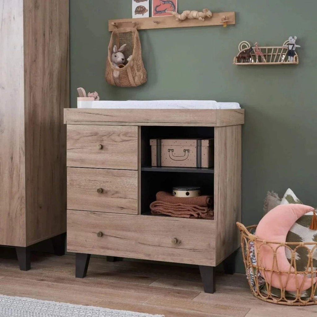 Distressed oak changing dresser with three drawers and open storage cubby.