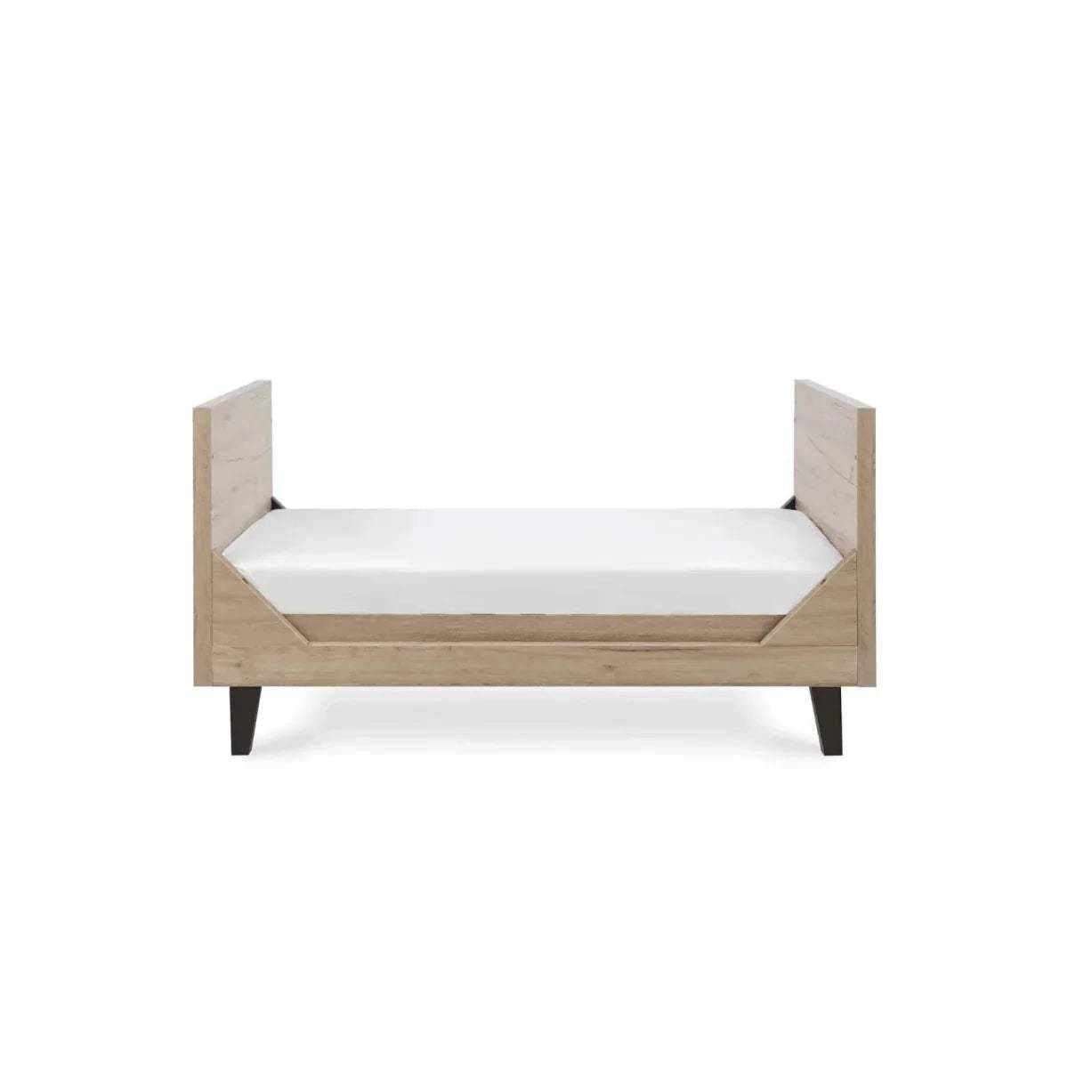 Distressed oak baby bed with white mattress and panel headboard, open slat sides