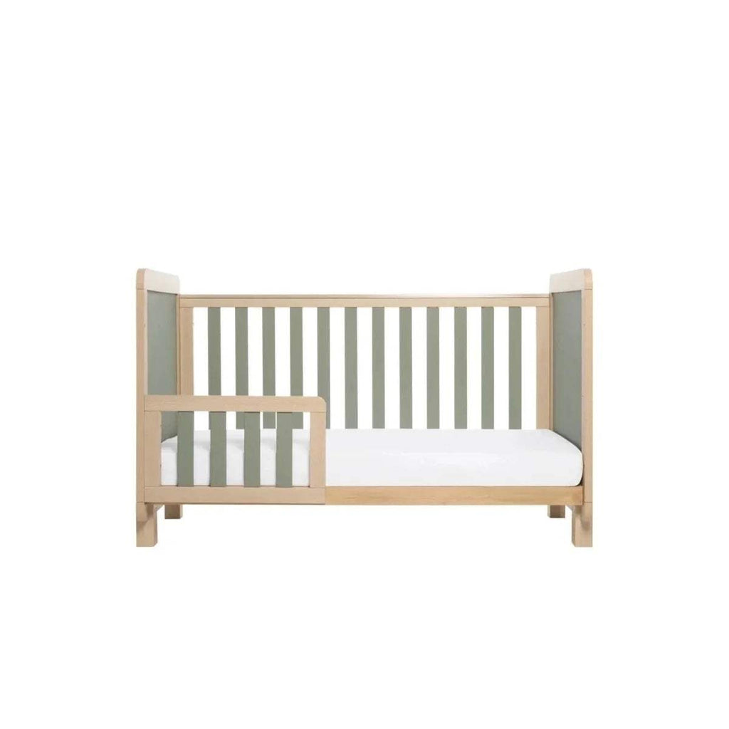 Golden oak bed with sage panel insert, white mattress, and vertical slats