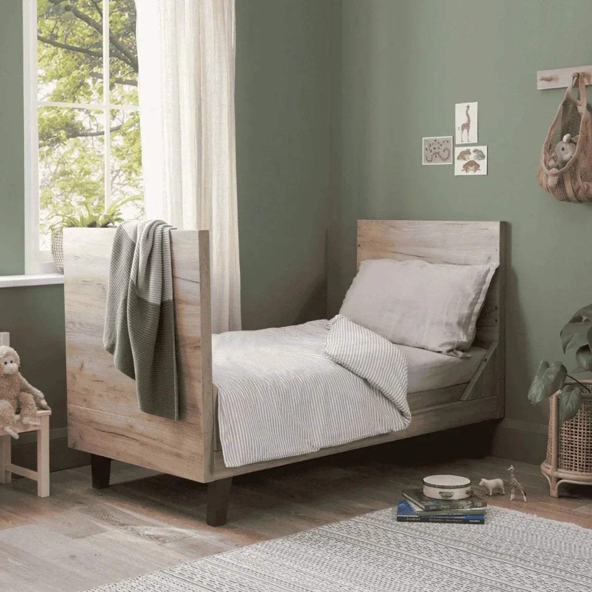 Distressed oak cot bed with white mattress, gray bedding, and slate grey slat sides