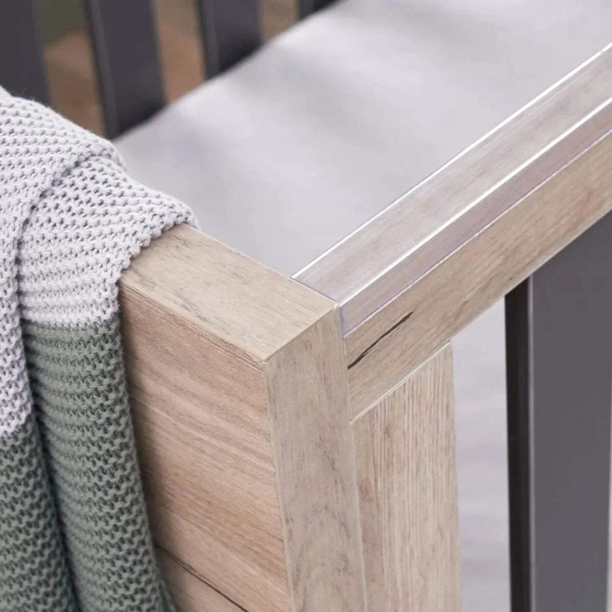 Close-up of distressed oak cot bed corner with slate grey slat frame