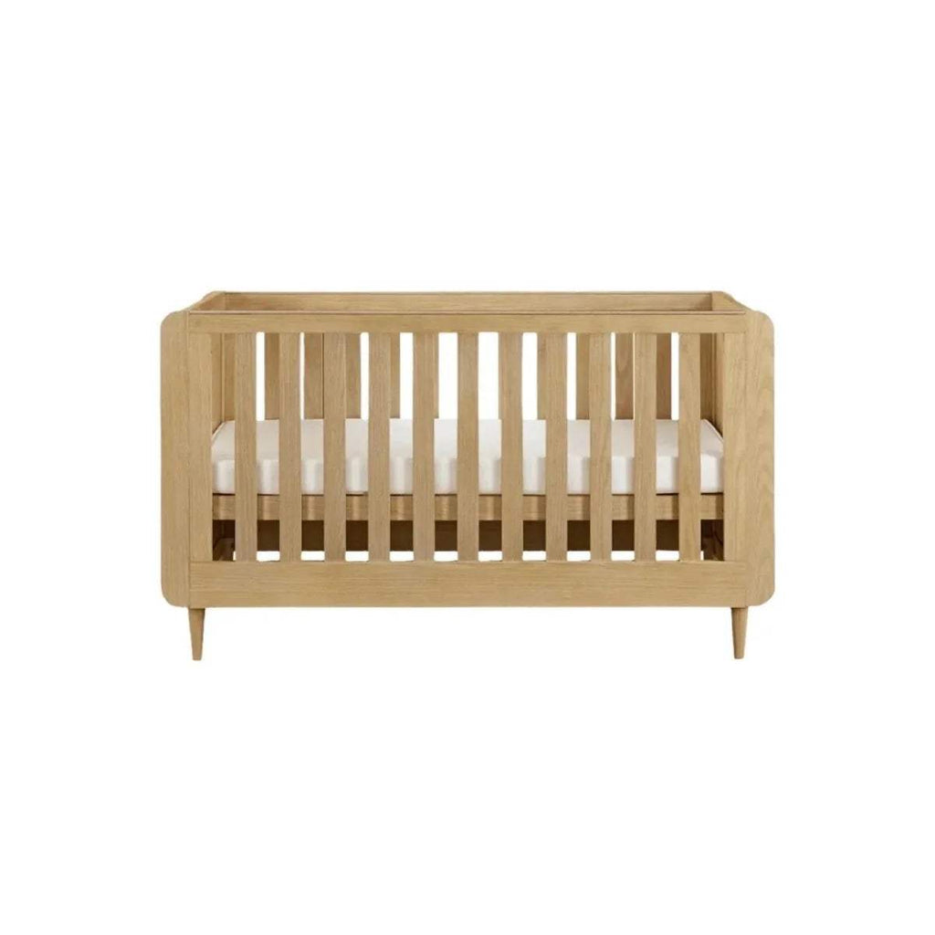 Light oak cot bed side view with vertical slat rails and solid end panels