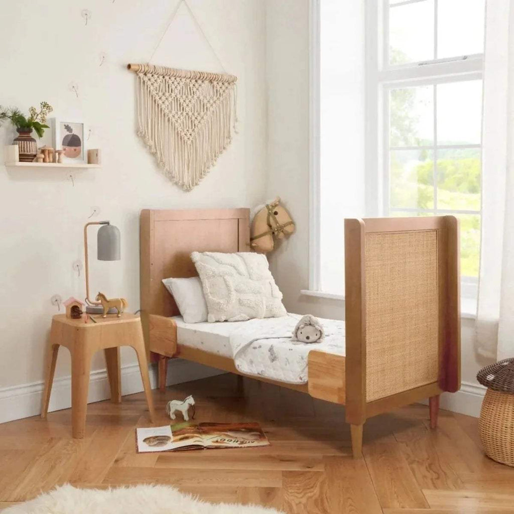 Light oak cot bed with woven panel end and vertical slat rails