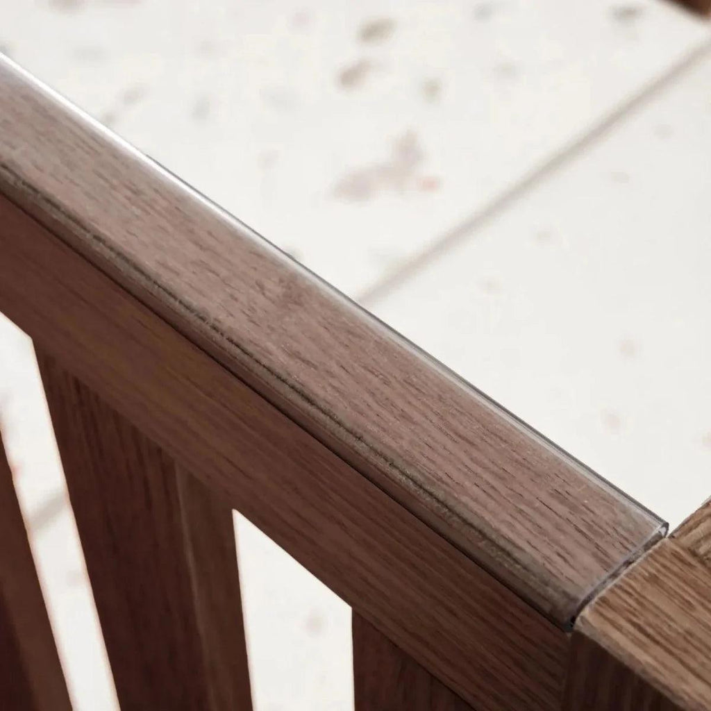 Warm walnut cot bed rail close-up with smooth rounded wood edge