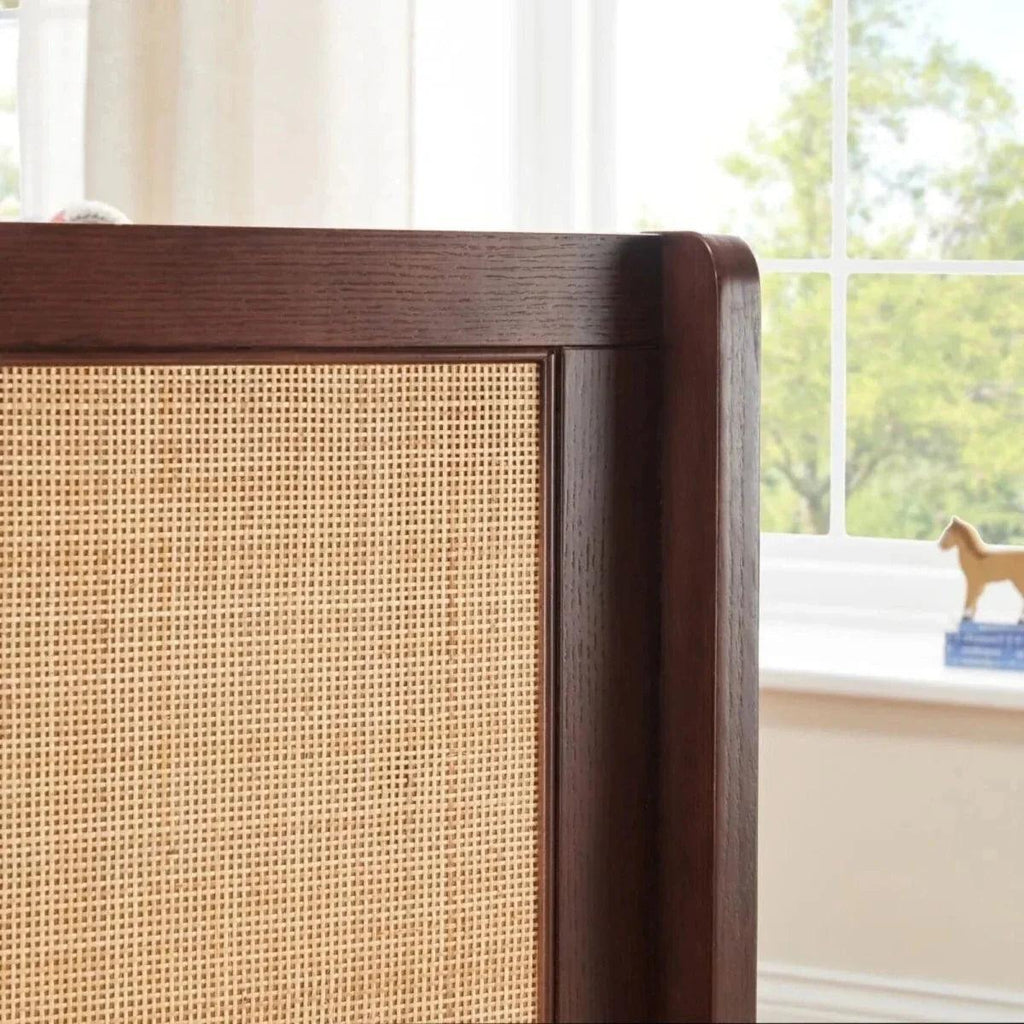 Warm walnut cot bed corner with woven panel and rounded wood trim