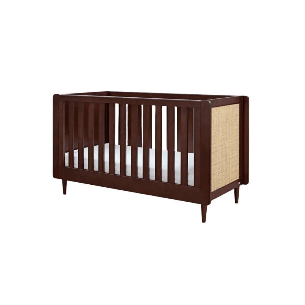 Warm walnut cot bed with vertical slat rail and woven side panel at the end