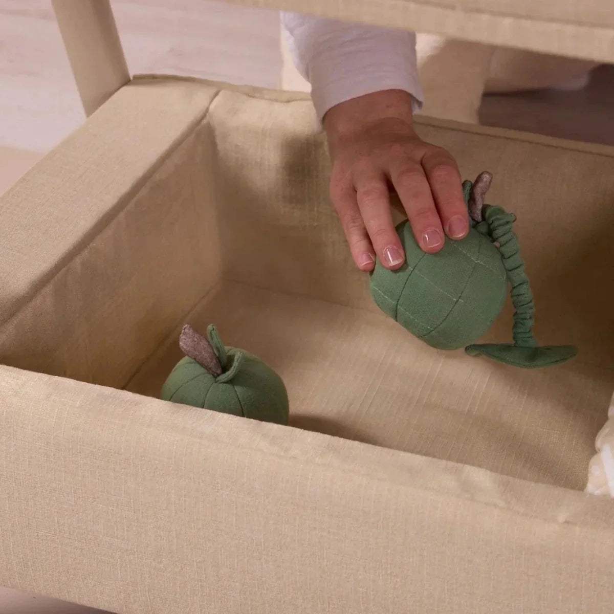 Sand bedside crib interior with padded base and small green toys