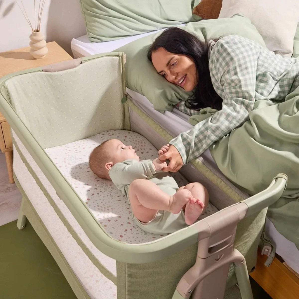 Eucalyptus green bedside crib with raised side rail, padded mattress, and open entry