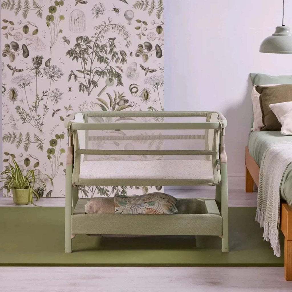 Eucalyptus green bedside crib with open front and cushioned mattress inside