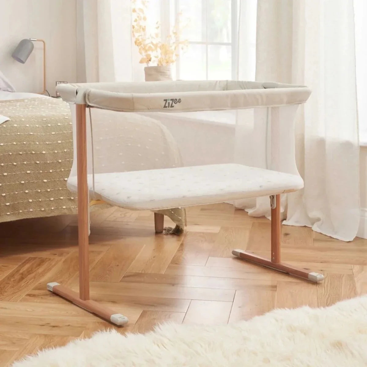 Ecru and walnut bedside crib with mesh sides and padded mattress base