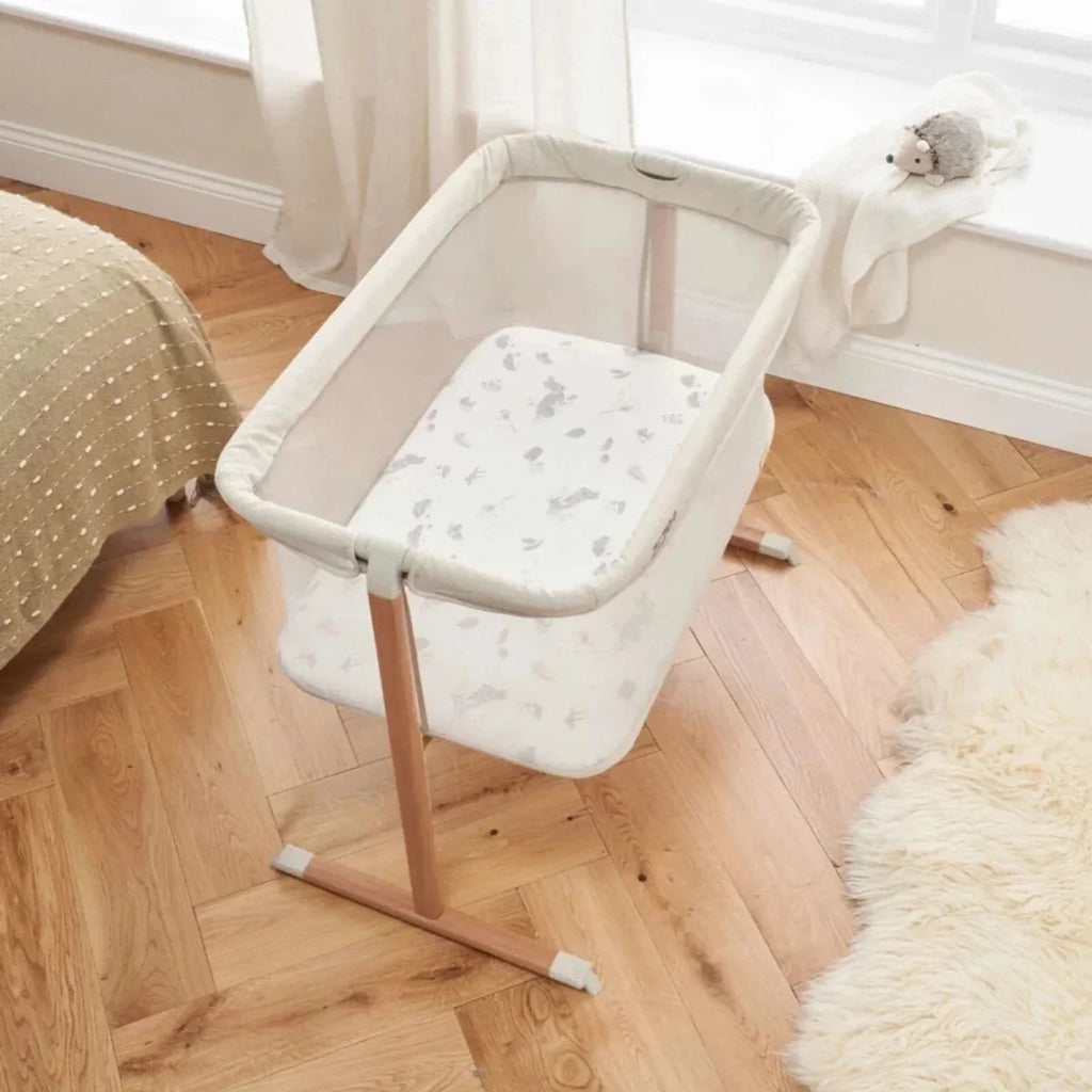 Ecru crib with padded sides and seat, walnut frame, and rocking base