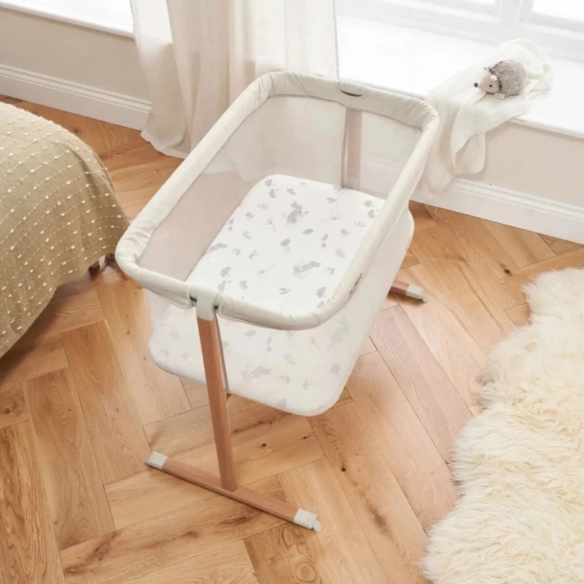 Ecru crib with padded sides and seat, walnut frame, and rocking base