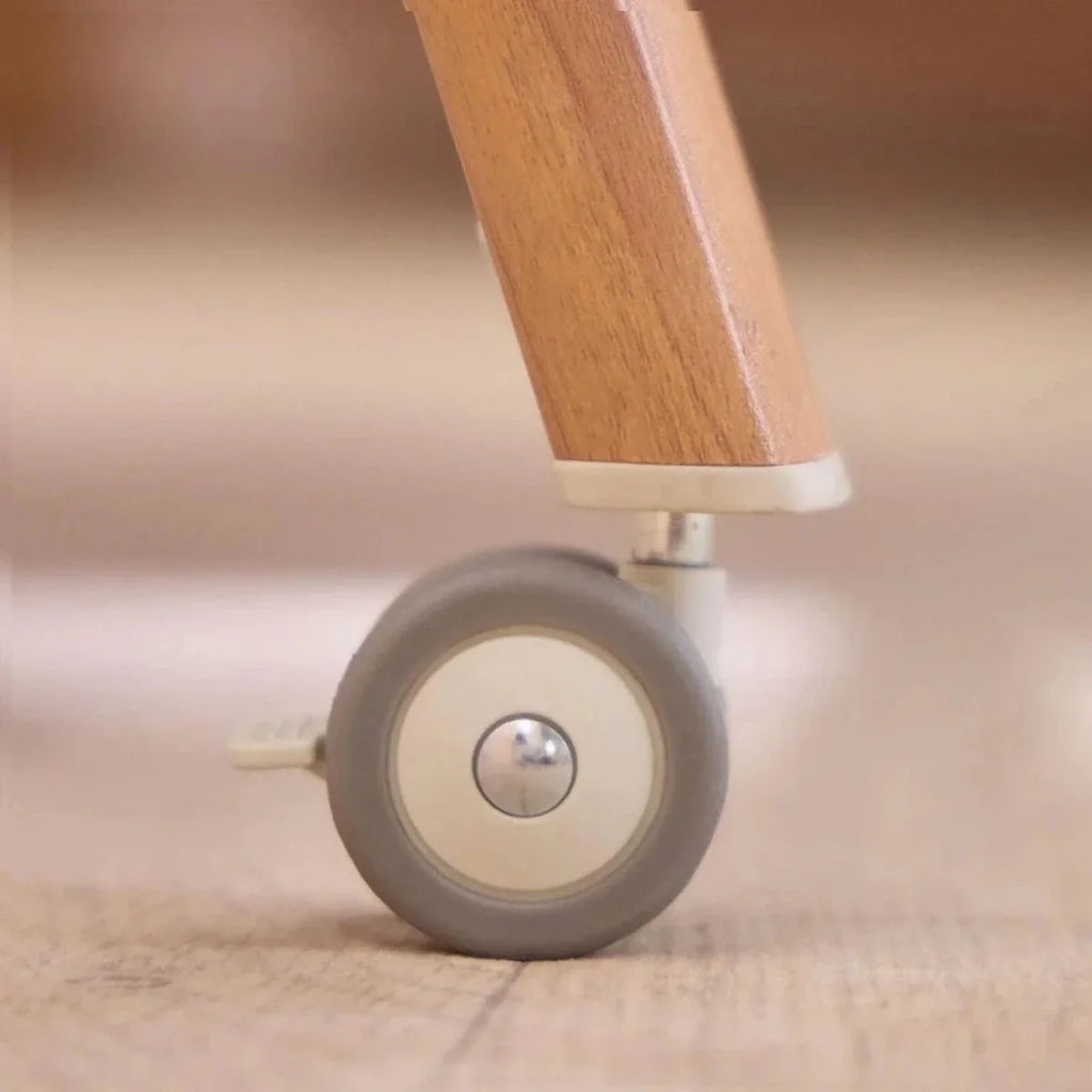Walnut leg and gray caster wheel base for bedside crib in ecru frame
