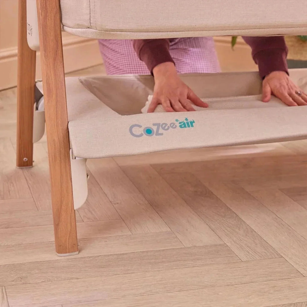 Ecru bassinet insert with Cozee air logo, on a bedside crib mattress platform