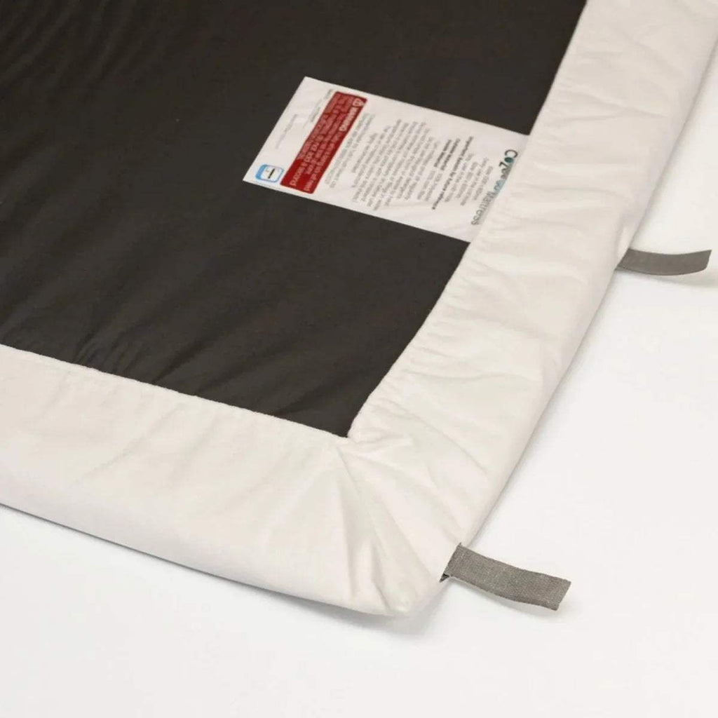 Corner detail of white fitted sheet showing dark waterproof layer and stitching.