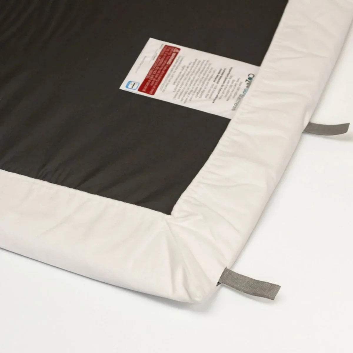 Corner detail of white fitted sheet showing dark waterproof layer and stitching.