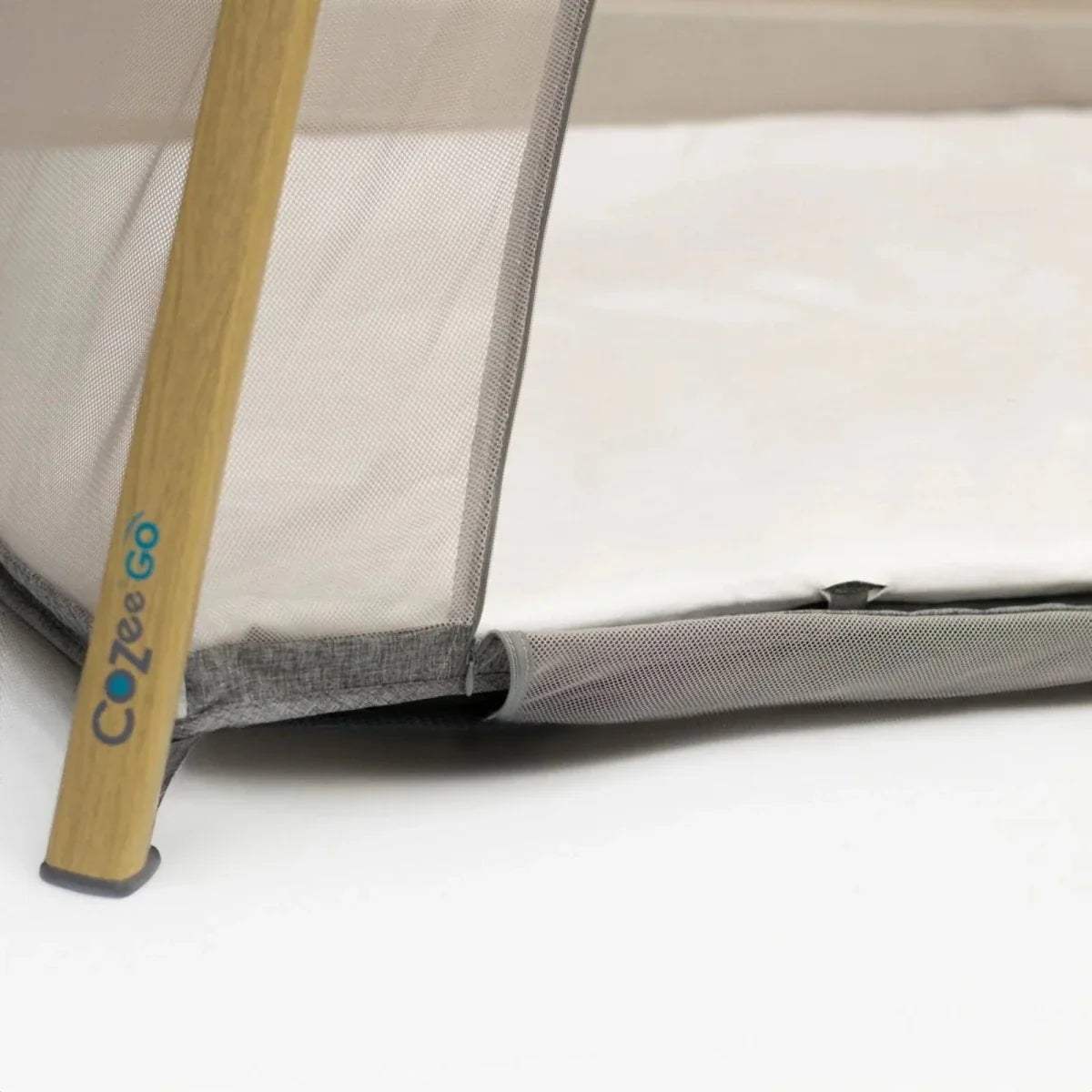 White waterproof fitted sheet with gray trim and corner fastener near bed frame.