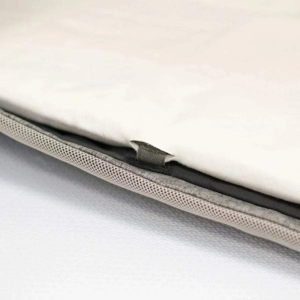 Close-up edge of white fitted sheet showing mesh layer and black seam line.